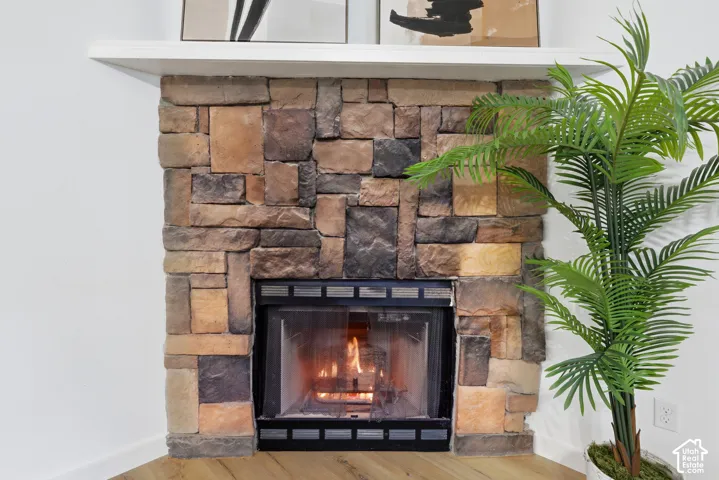 Corner fireplace featuring a multi-tonal stacked stone surround and a white built-in mantel