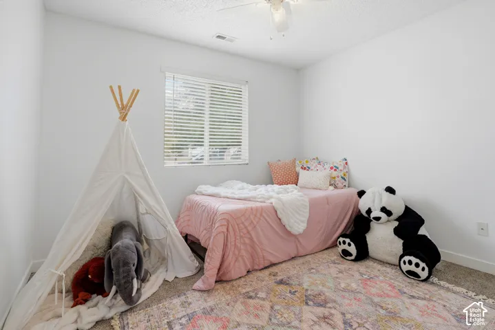 Neutral interior room featuring neutral-toned carpeting, white walls, a ceiling fan with integrated lighting, and a window with horizontal blinds