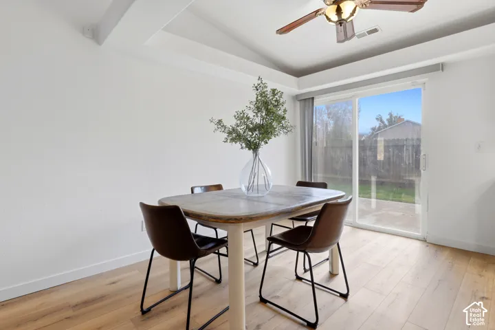 Vaulted ceiling featuring a central lighted ceiling fan, expansive sliding glass doors, and wide-plank wood-finish flooring
