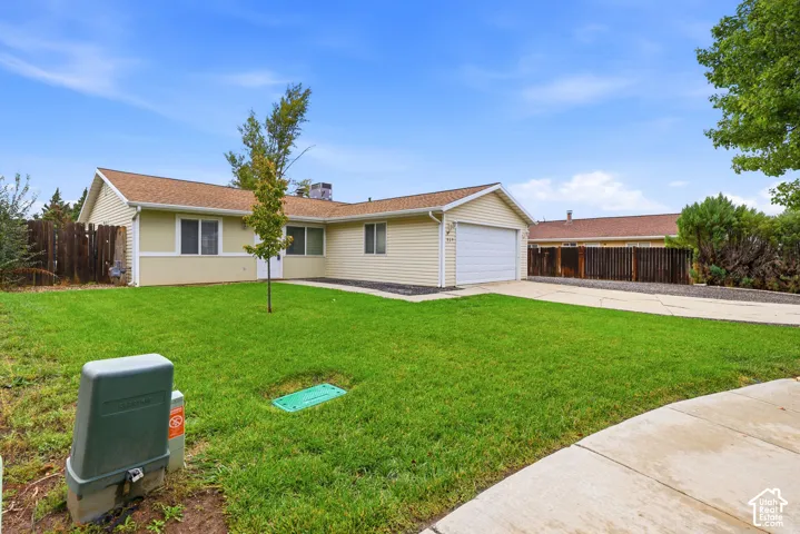 Single-story residence featuring light-colored horizontal siding, asphalt shingle roofing, attached two-car garage, concrete driveway, and wooden perimeter fencing
