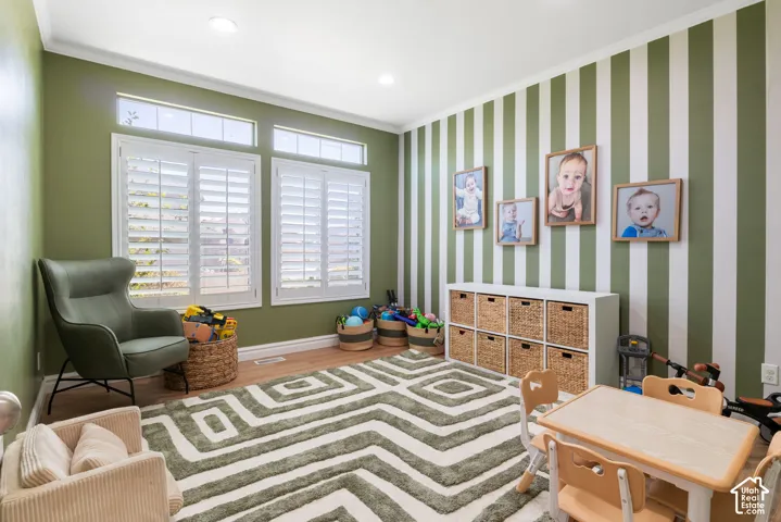Spacious interior room featuring wood-finish flooring and crown molding