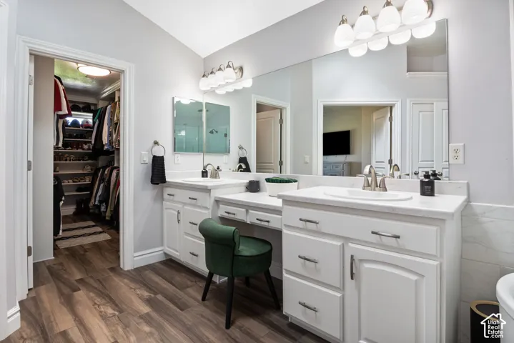 Bathroom featuring dual vanities with white cabinetry, integrated sinks, and brushed nickel fixtures