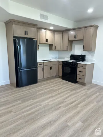 Kitchen featuring wood-finish cabinetry, white countertops, and black appliances