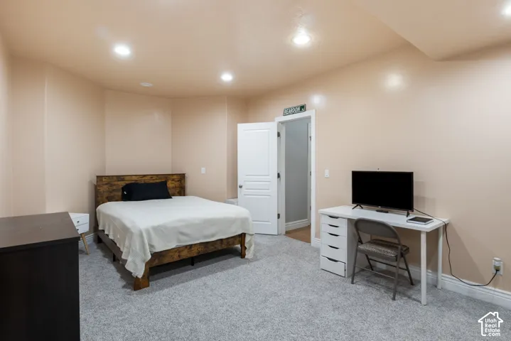 Recessed ceiling lighting illuminates the room, featuring light-toned walls and grey carpeting