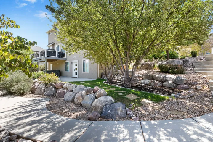Rear exterior featuring a ground-level patio, a second-story deck with glass railings, and a contemporary entry door