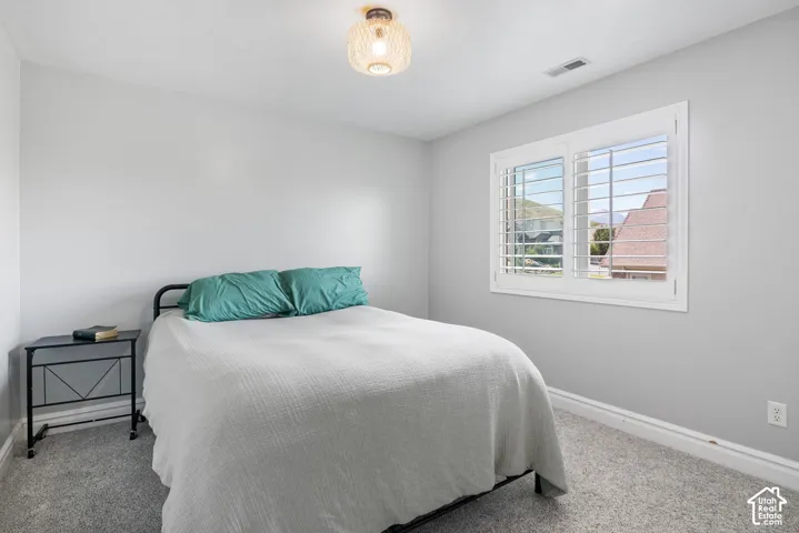 Carpeted room featuring light gray walls, white trim, a decorative ceiling light fixture, and a window with white plantation shutters