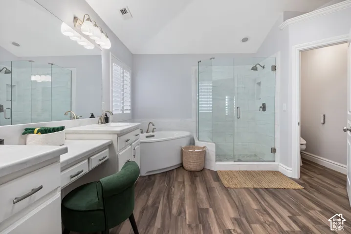 Spacious bathroom featuring wood-finish flooring, a glass-enclosed shower with tiled walls, and a corner soaking tub