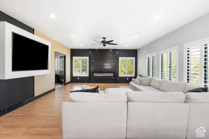 Spacious living area featuring wood-finish flooring, a contemporary linear fireplace, and recessed lighting