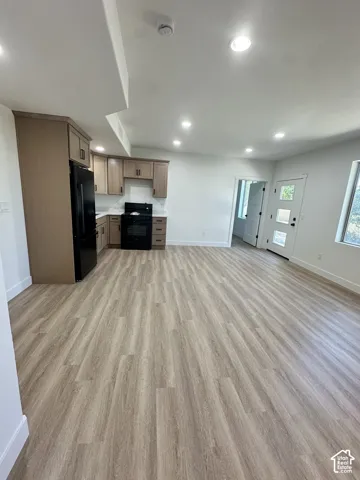 Open-concept living space with wood-finish flooring, recessed lighting, and a modern kitchen
