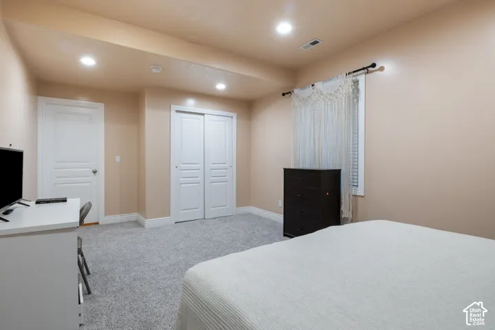 Recessed lighting illuminates neutral-toned walls and plush grey carpeting
