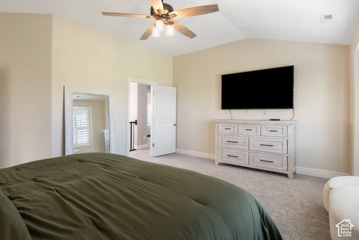 Vaulted ceiling with a ceiling fan, light-toned carpeting, and neutral wall paint