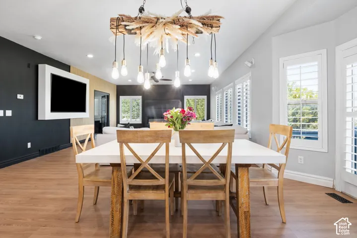 Open-concept dining area featuring wood-finish flooring, a decorative chandelier, and a built-in wall unit