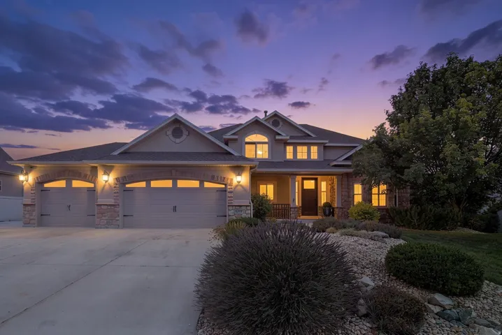 Stucco and stone exterior featuring multiple gabled rooflines, an arched entry, and a three-car garage