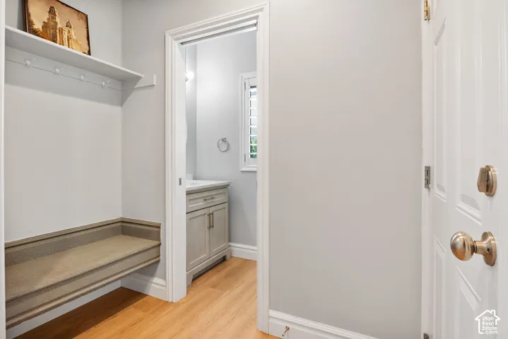 Entryway featuring built-in bench seating with a stone-finish surface, an integrated shelf with coat hooks, and light-toned wood-finish flooring