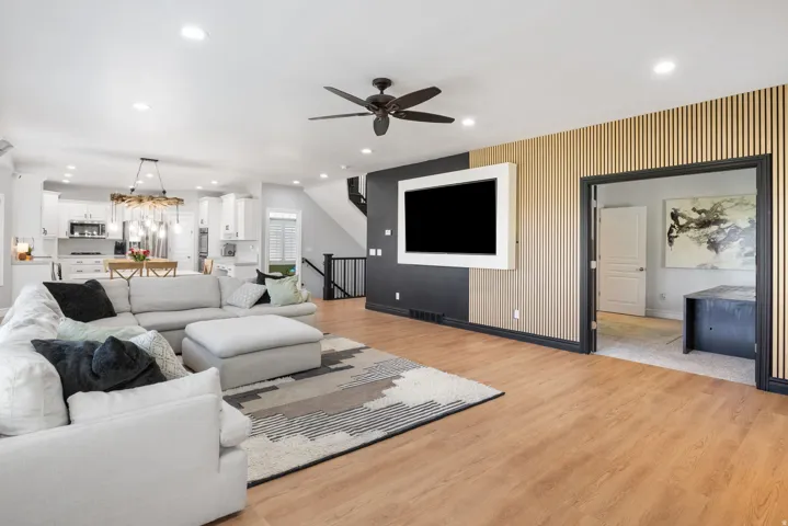 Open-concept living space featuring wood-finish flooring, recessed lighting, and a dark-toned ceiling fan