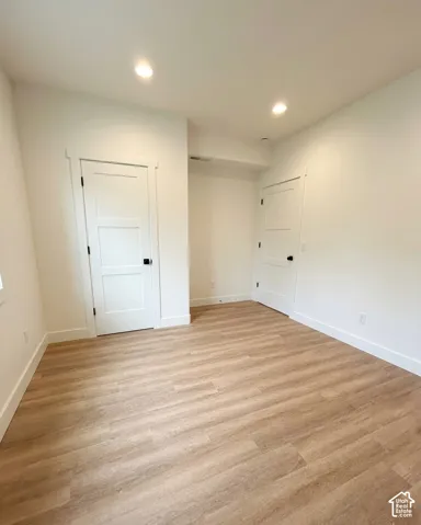 Spacious room featuring light wood-finish flooring and recessed ceiling lighting