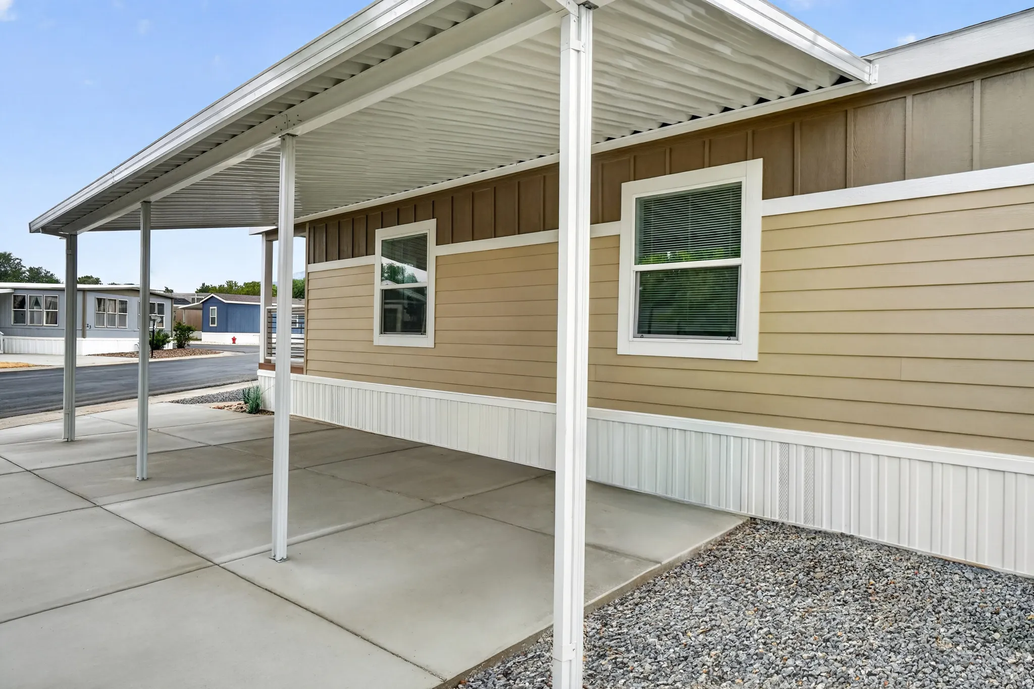 Exterior featuring light brown horizontal siding, vertical brown accent siding, white trim windows, and white foundation skirting