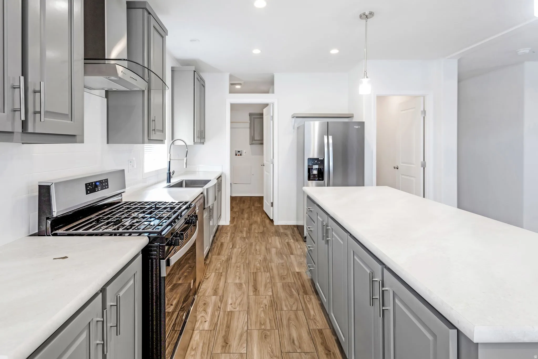 Kitchen featuring wood-finish flooring, recessed lighting, and a center island with a light-colored countertop