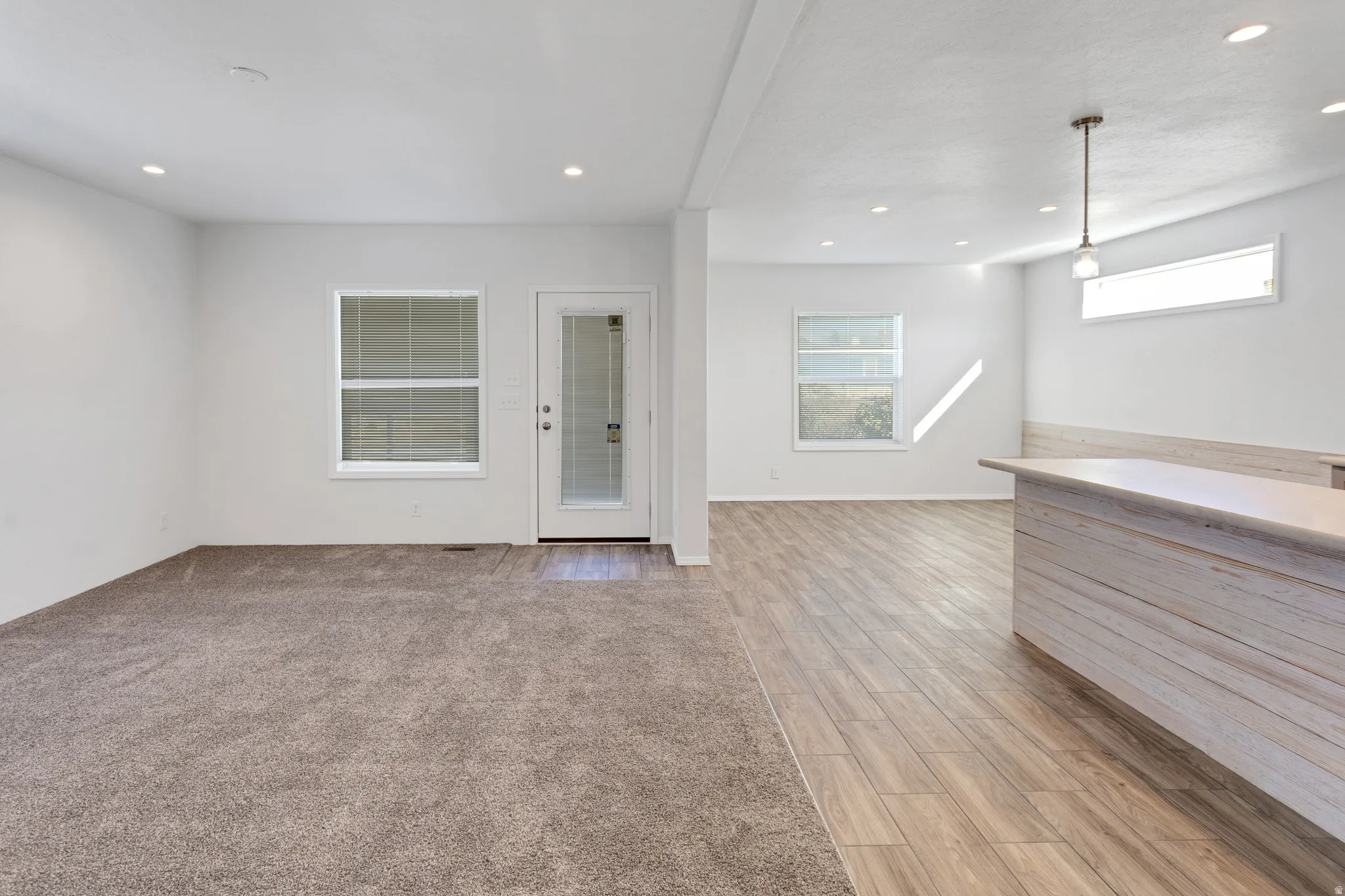 Open-concept interior featuring recessed lighting, a built-in breakfast bar with a light wood finish, and wood-finish flooring