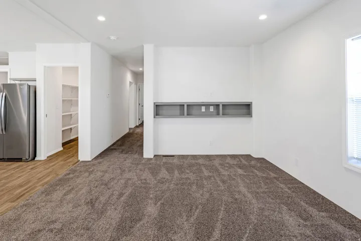 Carpeted living area with recessed lighting, a built-in media console, and a window with blinds