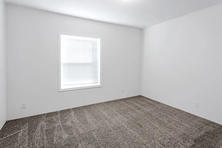Spacious room featuring neutral carpeting and a single window with blinds