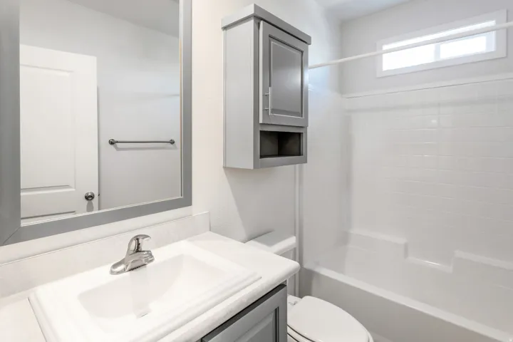 Full bathroom featuring a vanity with an integrated sink, a large framed mirror, and a wall-mounted storage cabinet