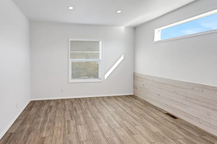 Spacious room featuring wood-finish flooring, recessed lighting, and a horizontal window with blinds