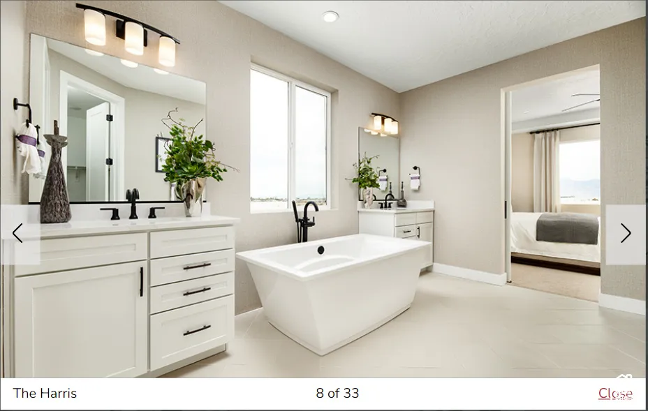 Freestanding soaking tub with a floor-mounted faucet, dual vanities with white cabinetry, and matte black fixtures