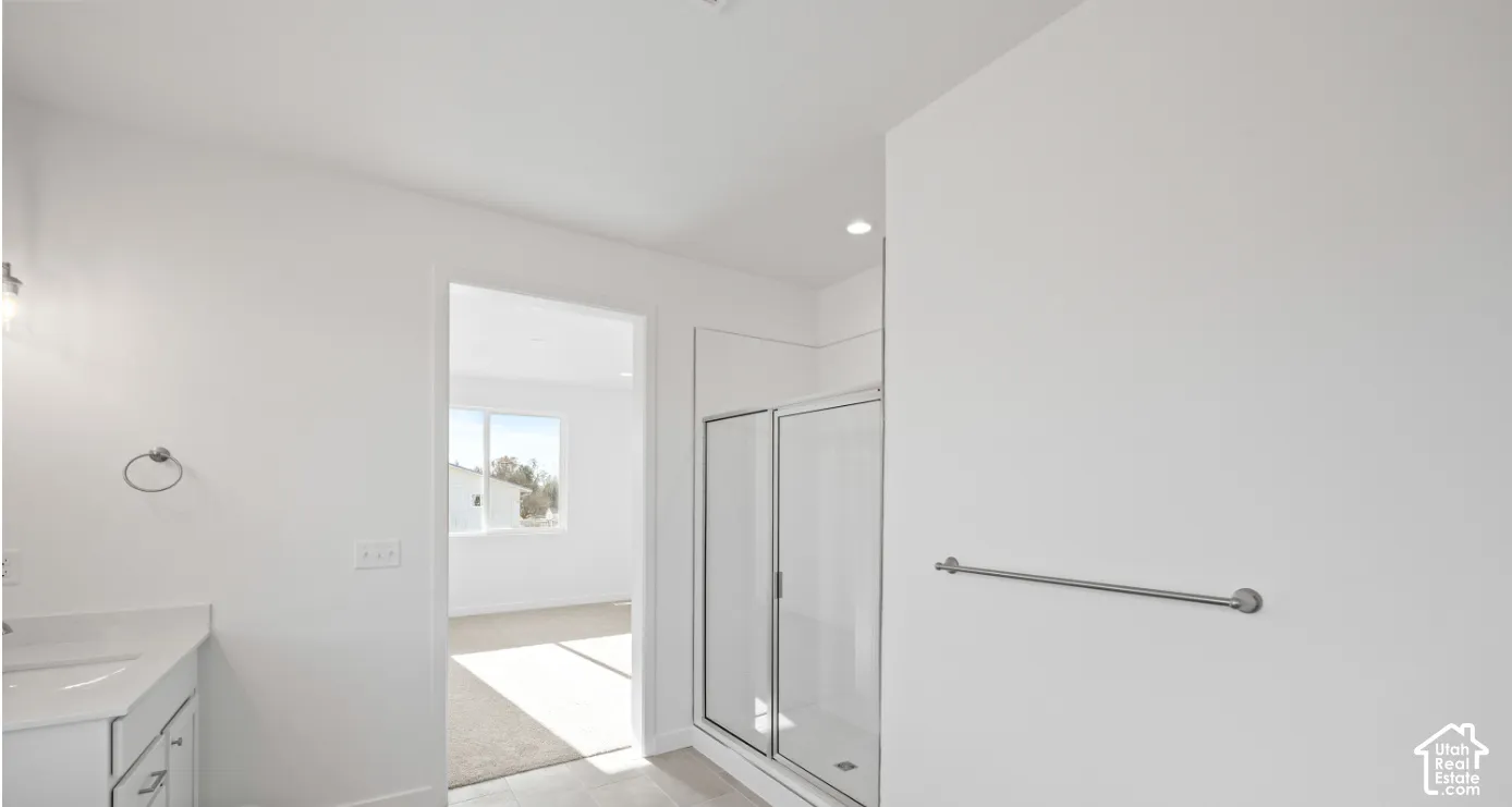 Modern bathroom featuring a glass-enclosed shower with a recessed light, a vanity with a white countertop and base cabinetry, and a chrome towel ring