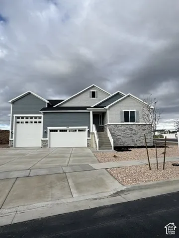Multi-level exterior featuring a combination of stone masonry and horizontal siding, a three-car garage, and concrete driveway