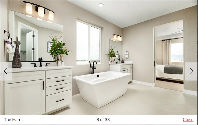 Freestanding soaking tub with a floor-mounted faucet, dual vanities with white cabinetry, and matte black fixtures