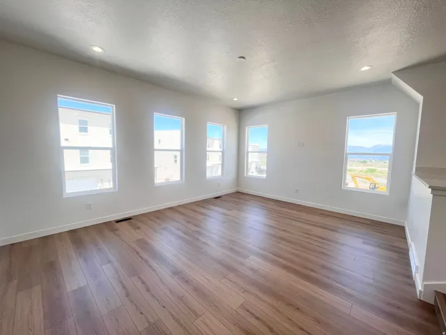 Spacious room featuring wood-finish flooring, white baseboards, and numerous windows