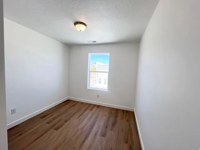 Room featuring wood-finish flooring, a double-hung window, and a flush mount ceiling light fixture