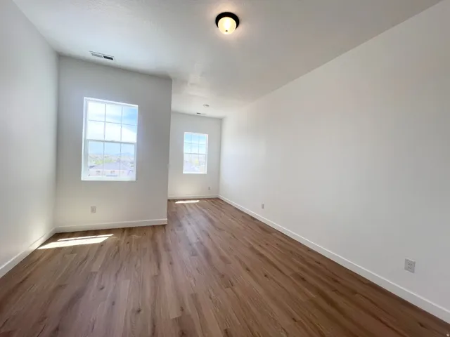 Bright interior space featuring wood-finish flooring, white walls, multiple windows, and a ceiling-mounted light fixture