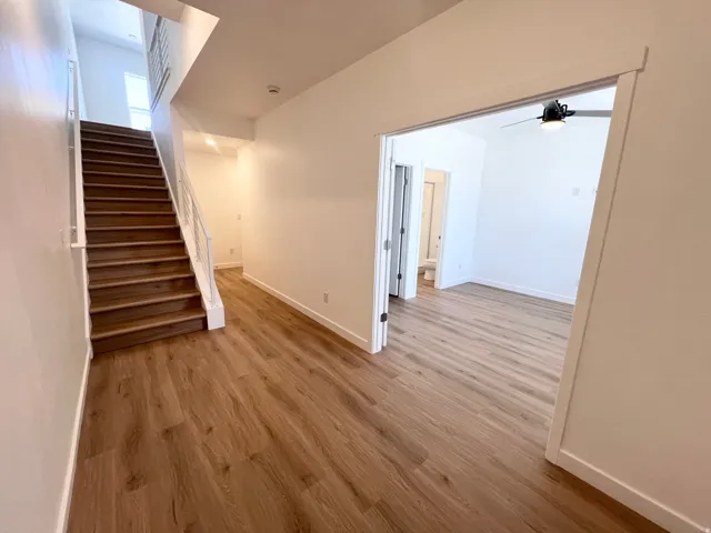 Spacious entryway featuring wood-finish flooring, a contemporary staircase with white railings, and recessed lighting