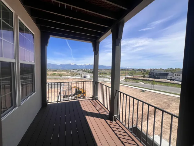 Covered balcony featuring wood-finish decking and black metal railings