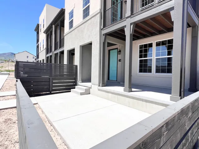 Exterior patio featuring a modern privacy fence, concrete paving, and a covered entry with a vibrant turquoise door