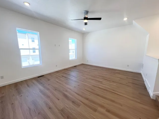 Spacious room featuring wood-finish flooring, recessed lighting, and a modern ceiling fan