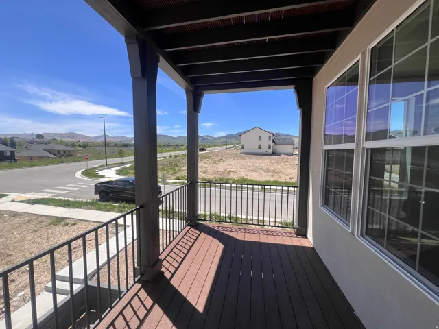 Covered front porch featuring wood-finish decking and black metal railings