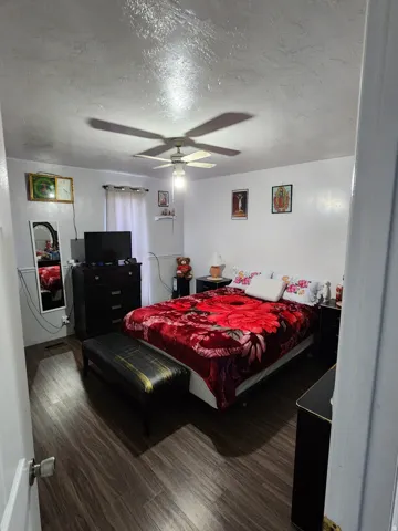 Bedroom featuring wood-finish flooring, a ceiling fan with integrated lighting, and white walls