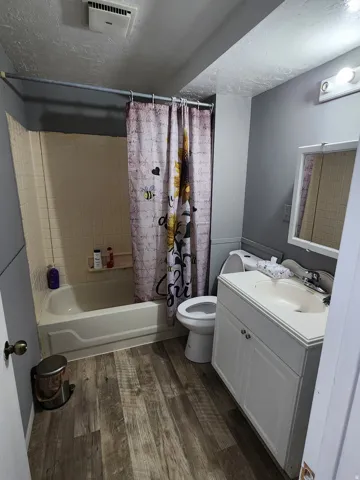 Bathroom with wood-finish flooring, a white tub, and a white vanity with an integrated sink