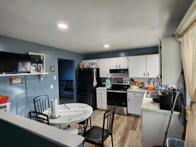 Kitchen featuring wood-finish flooring, white cabinetry, and stainless steel appliances