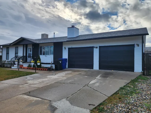 Exterior with white siding and dark trim, featuring a double garage with black doors