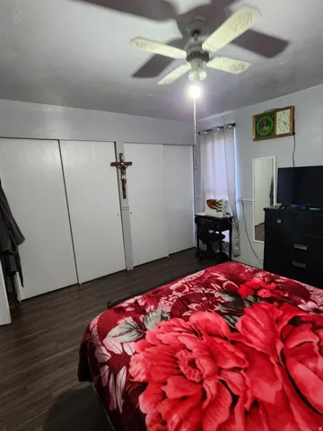 Interior room featuring wood-finish flooring, a ceiling fan with integrated lighting, and multiple bi-fold closet doors