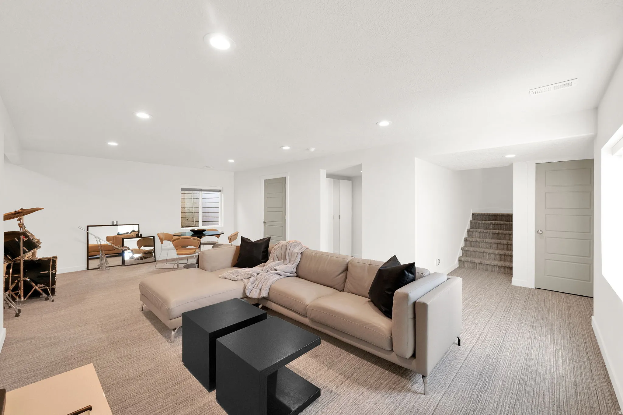 Open-concept lower level featuring recessed lighting and light-toned carpet flooring
