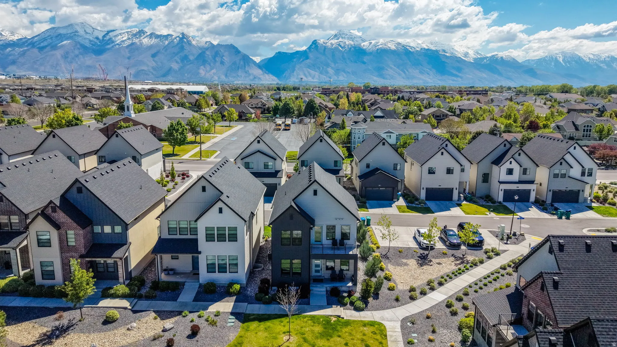 Contemporary residential development featuring a variety of modern home designs with dark shingle roofs, light-toned siding, and attached garages