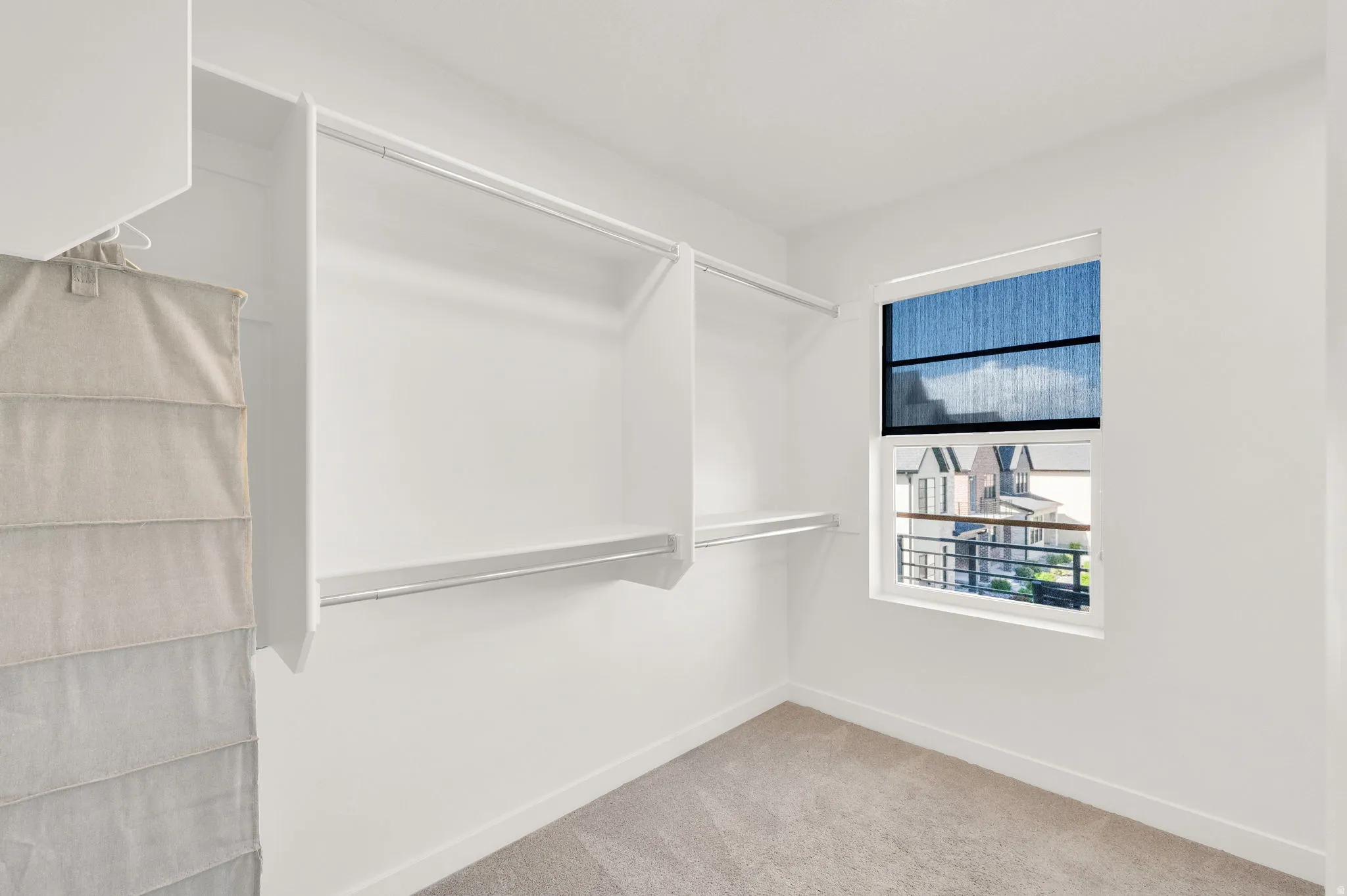 Spacious closet featuring white walls, carpeted flooring, and a large window