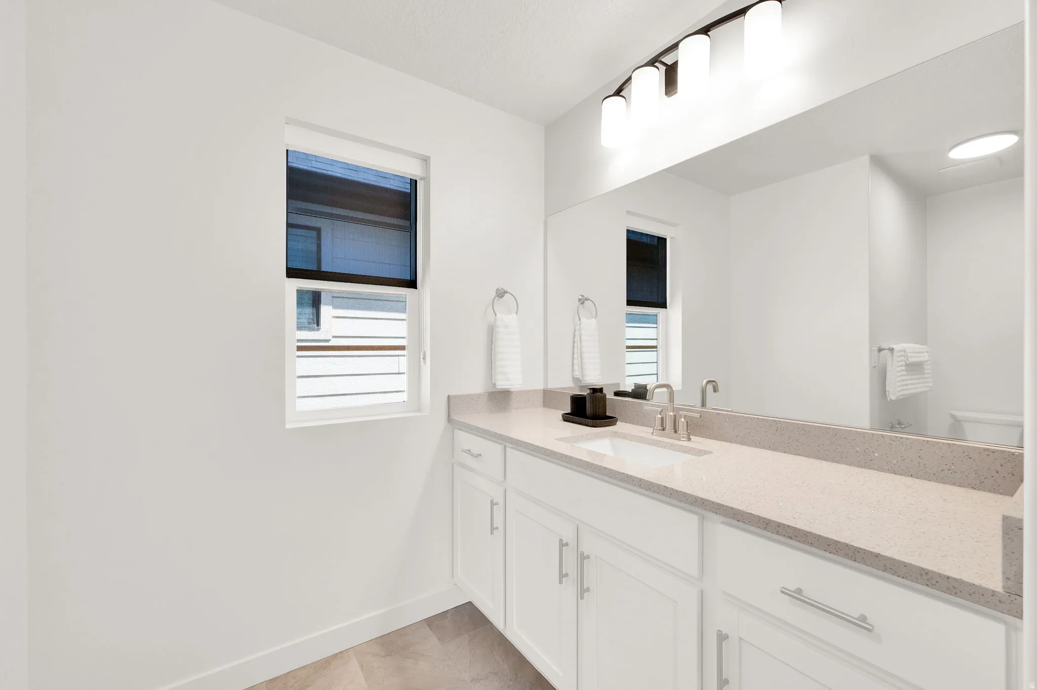 Bathroom vanity featuring a long countertop, undermount sink, and brushed nickel faucet