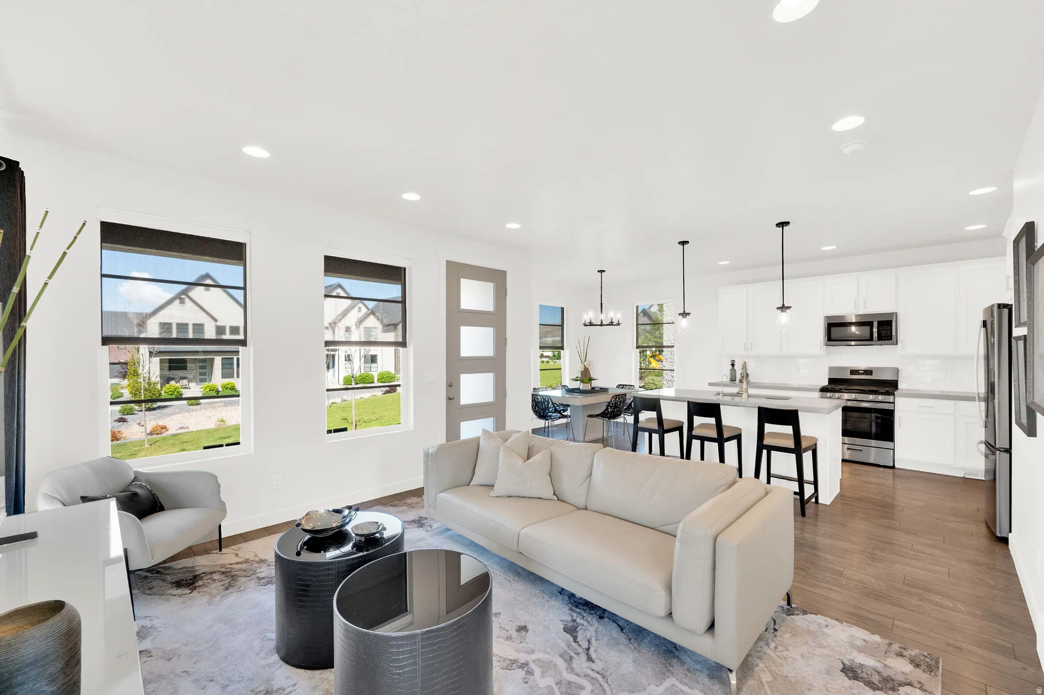 Open-concept living space featuring wood-finish flooring, recessed lighting, and large windows with black trim