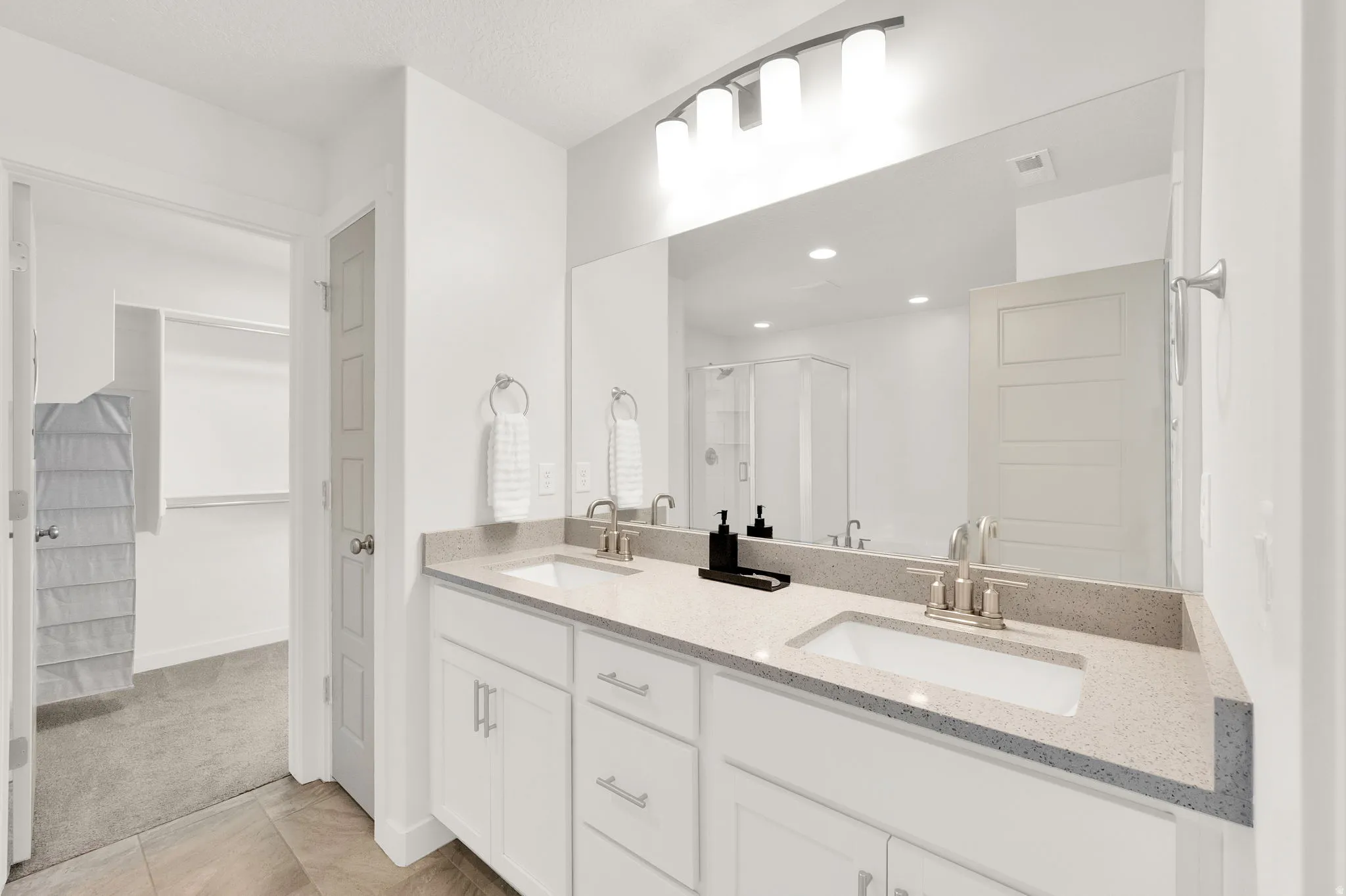 Dual vanity with undermount sinks, speckled stone countertops, and brushed nickel fixtures